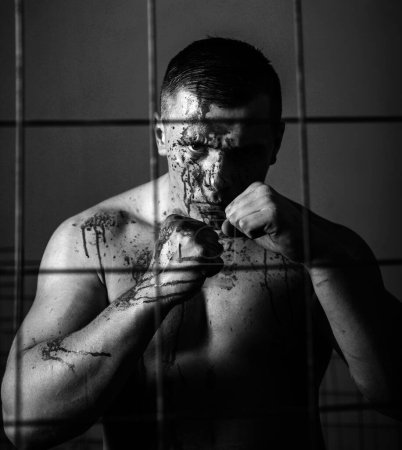 Photo for Psychic disease. Murderer brutal aggressive guy. Fight and attack. Aggressive person. Strong aggressive monster behind grid. Bodybuilder nude torso soiled blood. Prison for monster. Psycho mad man. - Royalty Free Image