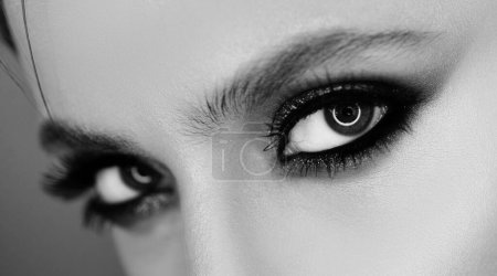 Téléchargez les photos : Beauté yeux de femme. Jolie femme avec des cils parfaits. Concept visage beauté féminine pour les yeux. Un maquilleur professionnel peint les yeux en studio - en image libre de droit