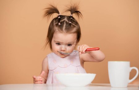 Photo for Portrait of cute Caucasian child kid with spoon. Hungry messy baby with plate after eating puree. Baby eating kids food - Royalty Free Image