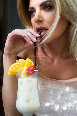 Foto de Sexy woman wearing a white dress drink cocktail with ice. Charming lady enjoying free summer beverage - Imagen libre de derechos