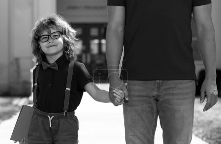Photo for Father walking son to school. Parent and nerd pupil of primary school schoolboy with backpack - Royalty Free Image