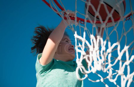 Foto de Juego de niños de baloncesto. Lindo niño pequeño sosteniendo una pelota de canasta tratando de hacer una puntuación - Imagen libre de derechos