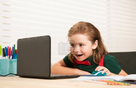 Photo for School boy with a happy smiling face studying and using computer laptop and writing on notebook. Nerd funny pupil - Royalty Free Image
