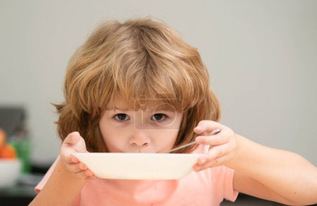 Téléchargez les photos : Un enfant mange. Petit garçon affamé en bonne santé mangeant de la soupe avec une cuillère. mignon curieux faim drôle gosse - en image libre de droit