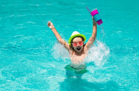 Téléchargez les photos : Un enfant qui boit du coctail dans la piscine. Petit garçon dans la piscine. Les enfants nagent en vacances d'été. Plage mer et l'eau amusant. Cocktail été enfants - en image libre de droit