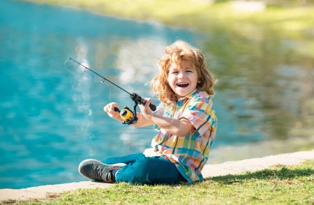 Foto de Gracioso niño feliz pesca el fin de semana. Un pescador se para en el lago con una caña de pescar y captura peces - Imagen libre de derechos