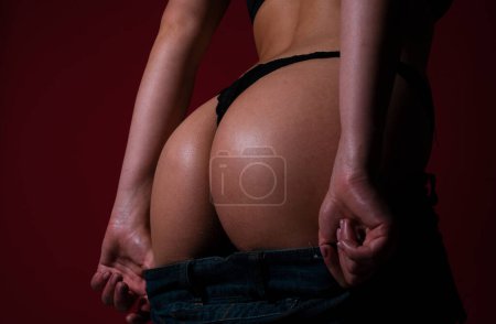 Foto de Sexy lingerie, close up butt in thong bikini, seduction buttocks. Undressed jeans, denim - Imagen libre de derechos