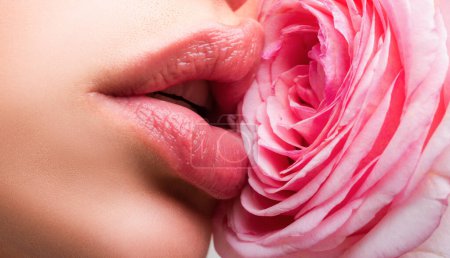 Foto de Hermosa cara de cerca con labios de color rosa brillante y una rosa cerca de la mejilla. Hermosos labios de mujer con rosa - Imagen libre de derechos