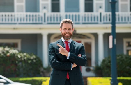 Photo for Busines sman standing outside a modern house. Real estate concept. Agent ready to sell home - Royalty Free Image