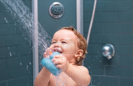 Téléchargez les photos : Bébé enfant drôle baigné de mousse et se lavant dans la baignoire à la maison. Joyeux enfant sous la douche - en image libre de droit