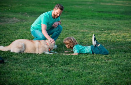 Téléchargez les photos : Heureux père et son fils jouant avec le chien dans le parc d'été - en image libre de droit