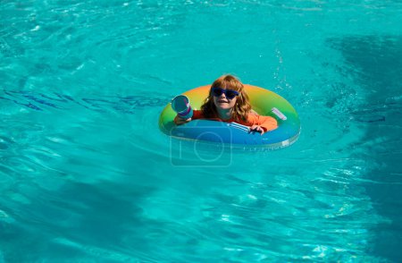 Foto de Niño en la piscina jugando en el agua, espacio de copia. Vacaciones y viajes con niños. Los niños juegan al aire libre en verano. Niño con anillo flotante - Imagen libre de derechos