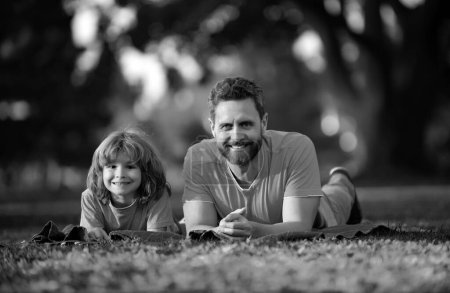 Téléchargez les photos : Père avec fils se détendre sur l'herbe verte - en image libre de droit