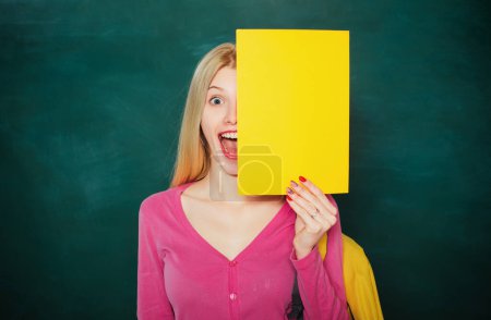Photo for Portrait of young caucasian female teacher or student. Cheerful teacher on lesson. Teaching. Student girl holding empty faper for product - Royalty Free Image