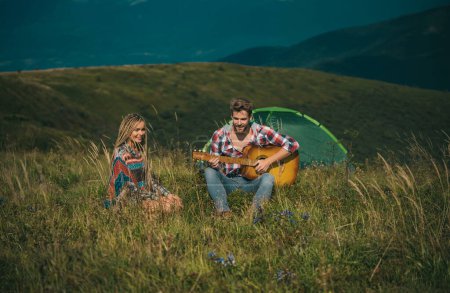 Téléchargez les photos : Couple romantique joue de la guitare sur le camping. Aventure en plein air avec des amis sur la nature. Amateurs de couples campant en forêt en été - en image libre de droit