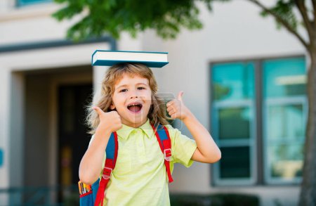 Foto de Retrato de niño lindo de escuela con gafas y una camisa con libro de asideros. Colegial nerd al aire libre - Imagen libre de derechos