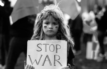 Téléchargez les photos : Un enfant tenant un panneau avec des mots "Arrêtez la guerre debout à l'extérieur". Poutine attaque le peuple ukrainien. Manifestation humaine - en image libre de droit