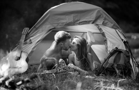 Foto de Pareja romántica acampando en paisaje primaveral. Sexy pareja de viajes besos en vacaciones campamento. Aventura para los amantes jóvenes campistas en la naturaleza. Pareja joven enamorada abrazándose y besándose - Imagen libre de derechos