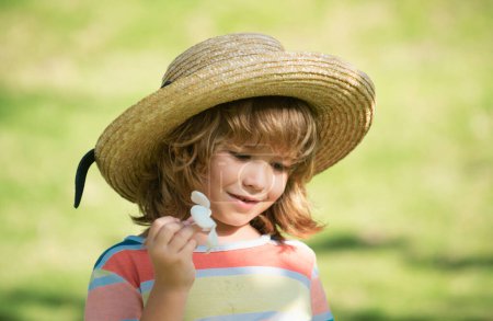 Téléchargez les photos : Portrait d'enfants, gros plan tête de mignon enfant en chapeau de paille avec fleur de plumeria - en image libre de droit