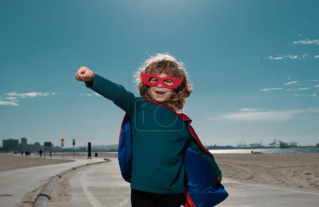 Téléchargez les photos : Le gamin s'amuse dehors en super manteau d'homme. Un garçon jouant au super héros. Succès et concept gagnant - en image libre de droit