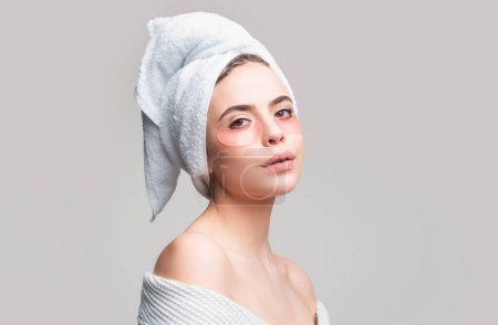 Photo for Woman applying eye patches. Close up portrait girl with towel on head. Portrait of beauty woman with eye patches showing an effect of perfect skin. Brunette spa girl applying anti-fatigue mask - Royalty Free Image