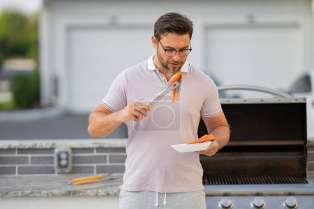 Photo for Man cooking meat on barbecue in the backyard of the house. Handsome man preparing barbecue. Barbecue chef master. Cook preparing delicious grilled barbecue food, bbq salmon fillet. Grill and barbeque - Royalty Free Image