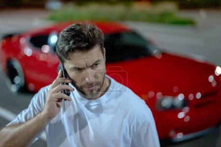 Photo for Angry man talking on phone on night urban street. Dangerous aggressive man talking on phone with serious face. Criminal city. Danger district. Aggressive angry man talking on phone outdoor. Night call - Royalty Free Image