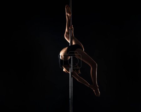 Téléchargez les photos : Pole danseur. Sexy girl fait des exercices de gymnastique sur la pole dance. Le pole dance est devenu une forme populaire de fitness. Flexibilité d'étirement. Pole dance. Pylône dansant la force, la flexibilité et la grâce - en image libre de droit