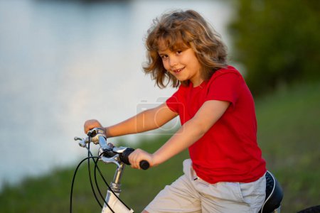 Photo for Kid riding bike. Boy riding bike in city park. Child first bike. Kid outdoors summer activities. Kid on bicycle. Little child riding bike in summer park on a driveway - Royalty Free Image