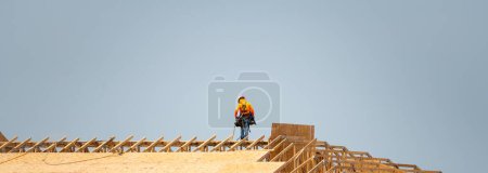 Photo for Wooden roof beam from framework. House roof at construction site. Roofer working on roof structure of building on construction site. Wooden roof beams. Roofing nails or screws for OSB sheets - Royalty Free Image