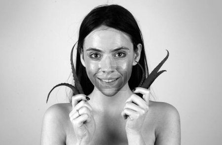 Téléchargez les photos : Belle femme tenir aloe vera, procédure faciale de boue cosmétique, concept de santé spa. Soins de la peau traitement de beauté. Serviette sur la tête. Boue minérale médicale - en image libre de droit