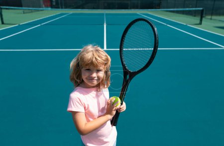 Téléchargez les photos : Joueur de tennis drôle sur le court de tennis. Enfant garçon avec raquette et balles de tennis - en image libre de droit