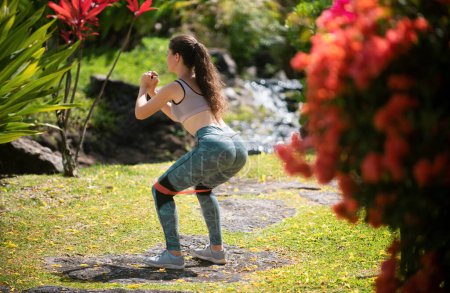 Téléchargez les photos : Jeune femme de fitness faisant des exercices de fitness dans le parc. Entraînement physique à l'extérieur. Cours de fitness en plein air. Entraînement femme en plein air. Concept de mode de vie sain - en image libre de droit