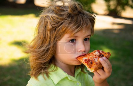 Photo for Boy eating pizza. Child pleasure and takes a bite of pizza - Royalty Free Image