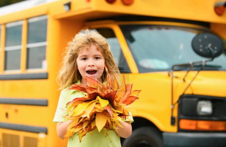 Foto de Back to school in september. Autumn child near school bus. Fall foliage. Schooler school boy in fall autumn park - Imagen libre de derechos