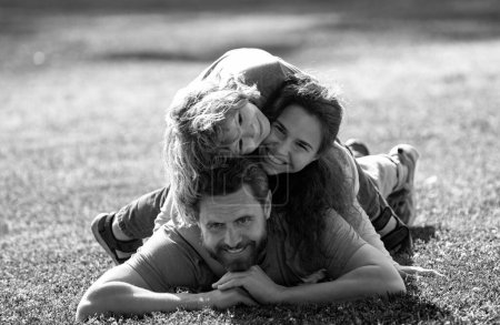 Téléchargez les photos : Joyeux câlin familial et embrasser sur la promenade d'été. Père mère et enfant marchant dans le parc et profitant de la belle nature. Portrait de famille mignon - en image libre de droit
