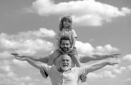 Foto de Abuelo con hijo y nieto levantando las manos o con los brazos abiertos volando. Familia Multi Generación. Día de los padres - Imagen libre de derechos