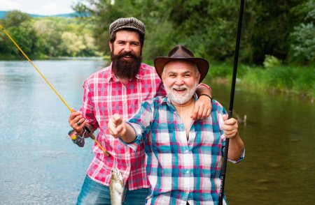 Téléchargez les photos : Des amis. Père et fils mature pêcheur pêche avec une canne à pêche sur la rivière - en image libre de droit