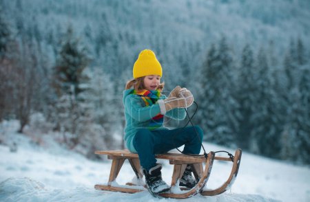 Photo for Active winter outdoors games for kids. Happy Christmas vacation concept. Boy enjoying winter, playing with sleigh ride on winter background of snow and frost - Royalty Free Image