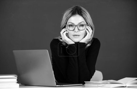 Photo for Concentrated attractive teacher. Portrait of smart young woman in glasses with book on the blackboard in class at high school or collage. Female student study in university - Royalty Free Image