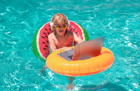 Photo for Happy little boy learning online computer laptop. Child relax and rest on colorful inflatable ring using computer in swimming pool. Work outside with laptop in pool - Royalty Free Image