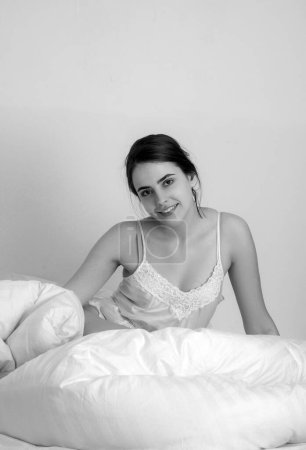 Photo for Young woman in the morning after good sleep in white comfortable bed, girl lying on soft pillows awaken in cozy bedroom, morning relaxation concept - Royalty Free Image