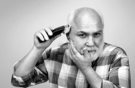 Photo for Portrait of old man being trimmed with hair clipper in barbershop, haircut with an electric razor. Man hair treatment - Royalty Free Image