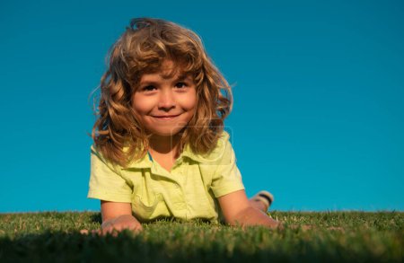 Foto de Dulce y feliz niño jugando en un césped en un parque en un manantial. Riendo, disfrutando de fresco - Imagen libre de derechos