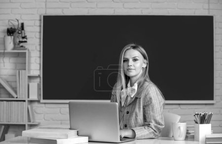 Téléchargez les photos : Jeune prof. Portrait d'une jeune étudiante qui étudie en classe sur fond de tableau noir - en image libre de droit