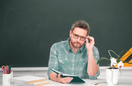 Téléchargez les photos : Portrait d'enseignant masculin enseignant ligne d'élèves du secondaire avec ordinateur portable dans la salle de classe sur tableau noir. Journée des enseignants - en image libre de droit