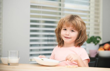 Photo for Portrait of cute child eating soup meal or breakfast having lunch by the table at home with spoon. Kids healthy food - Royalty Free Image