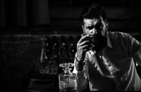 Photo for Young man holding glass of whiskey. Guy with beard holds brandy. Bearded drink cognac. Sommelier tastes drink. Man holding a glass of whisky. Sipping whiskey. Degustation, tasting. - Royalty Free Image