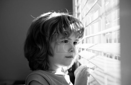 Foto de Protéjase. Quédate en casa en aislamiento. COVID-19 Lockdown. Un niño solitario mirando por la ventana. Concepto de cuarentena. Un chico triste en casa. pandemia de Coronavirus - Imagen libre de derechos
