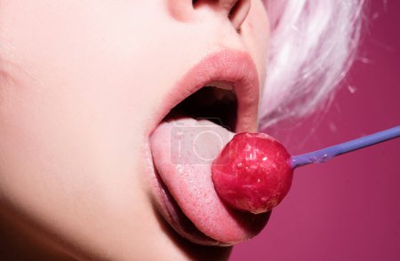 Photo for Licking candy. Lollipop model. Woman lips sucking a candy. Glamor sensual model with red lips eat sweats lolly pop - Royalty Free Image